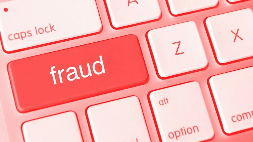 Teclado de computadora rojo con una tecla de 'fraude' destacada entre teclas más claras a su alrededor