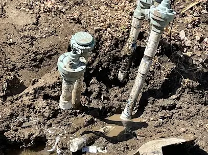 Tuberías y válvulas industriales de metal incrustadas en el suelo arenoso de un campo petrolero
