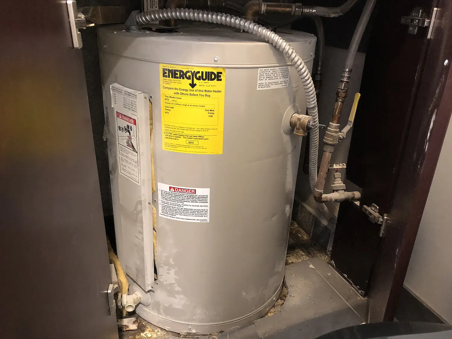 Calentador de agua de tipo tanque con etiqueta amarilla EnergyGuide y tubería metálica